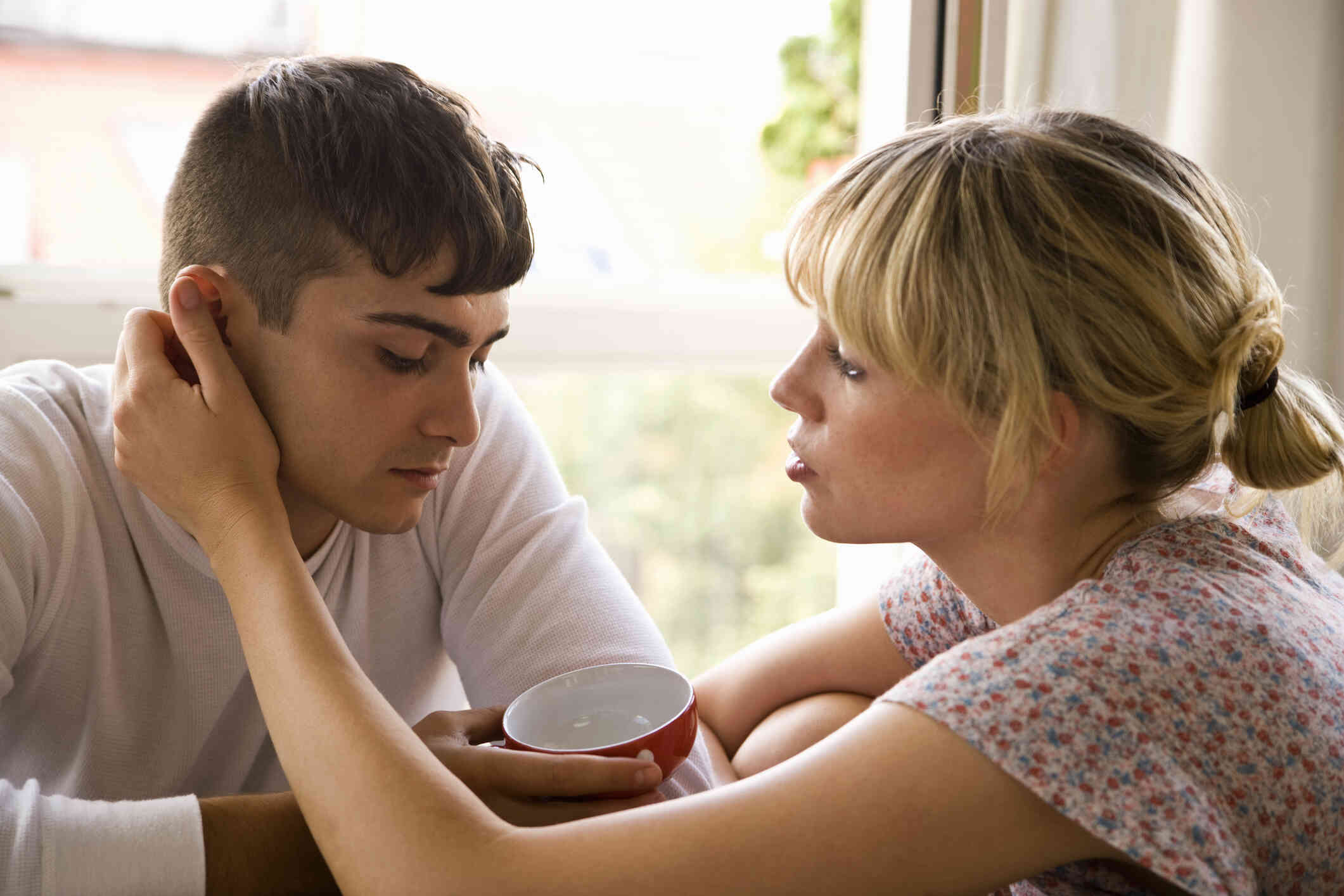 A woman reaches up to comfort her male partner.